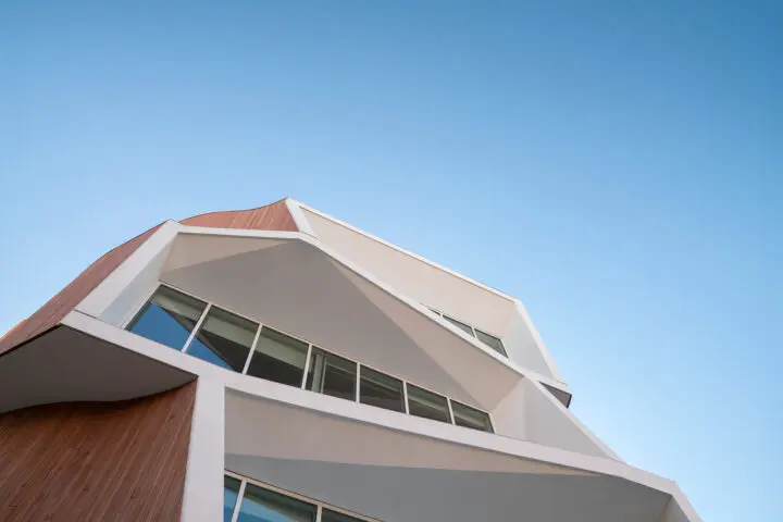 A close-up of an aperture from below frames the geometric frames against an open sky.