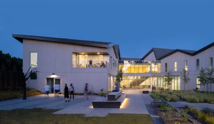 The north arm of the building terminates at a half-court basketball area backed by tiered bench seating.