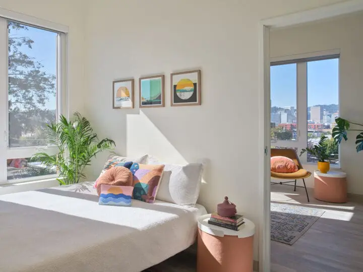 A sunlit bedroom is open to a living room with a view of Portland beyond.