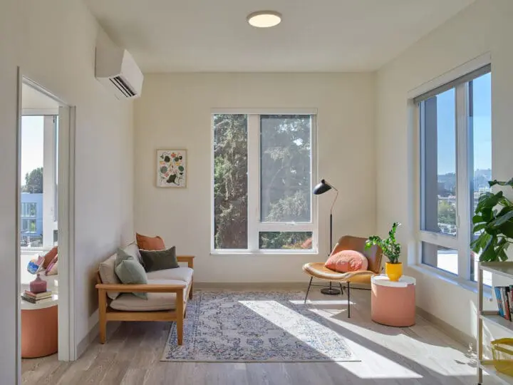 A cozy, daylit living room looks out to Portland through large windows.