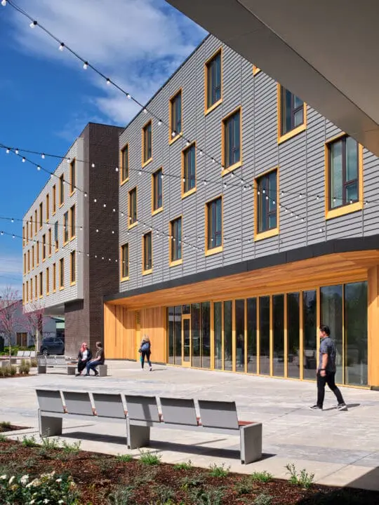 People enjoy the sun in 72Foster’s outdoor courtyard that connects to the ground-floor community room.