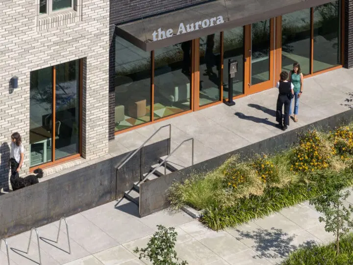 Birds-eye view of the front entrance of a cream and charcoal-colored brick apartment building, The Aurora.