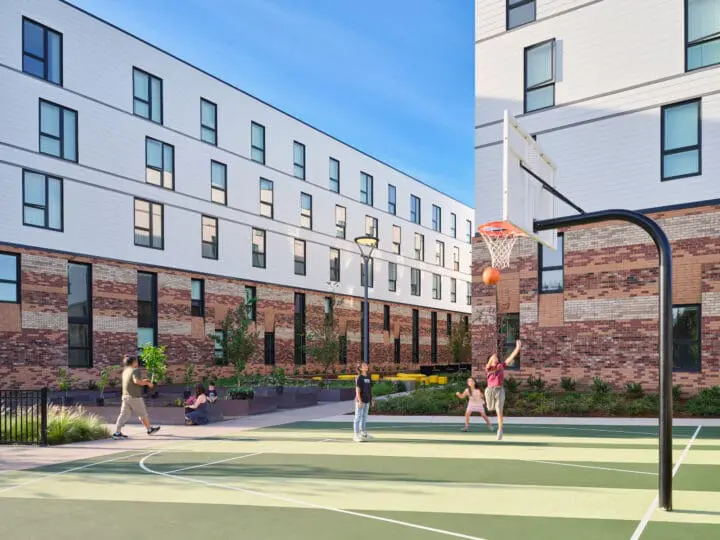 Children shoot hoops in a half-court basketball area at the end of the building.