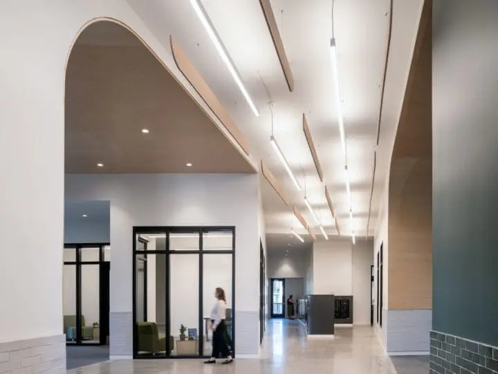Looking along the short length of the central lobby, linear lights and baffles travel towards a low wall of mailboxes.